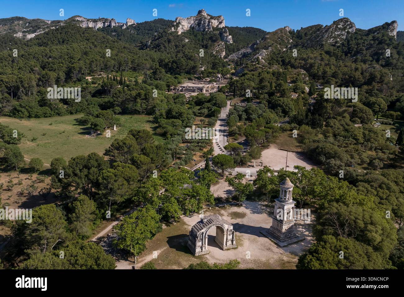 Francia, Bouches du Rhone, Parco naturale regionale delle Alpilles, Saint Remy de Provence, les Antiques de Glanum, cenotafio gallo-romano eretto tra il -30 e il -20 a.C. in memoria di un uomo della famiglia Julii e dell'arco municipale di Glanum (arco trionfale romano), sito archeologico di Glanum sullo sfondo (vista aerea) Foto Stock