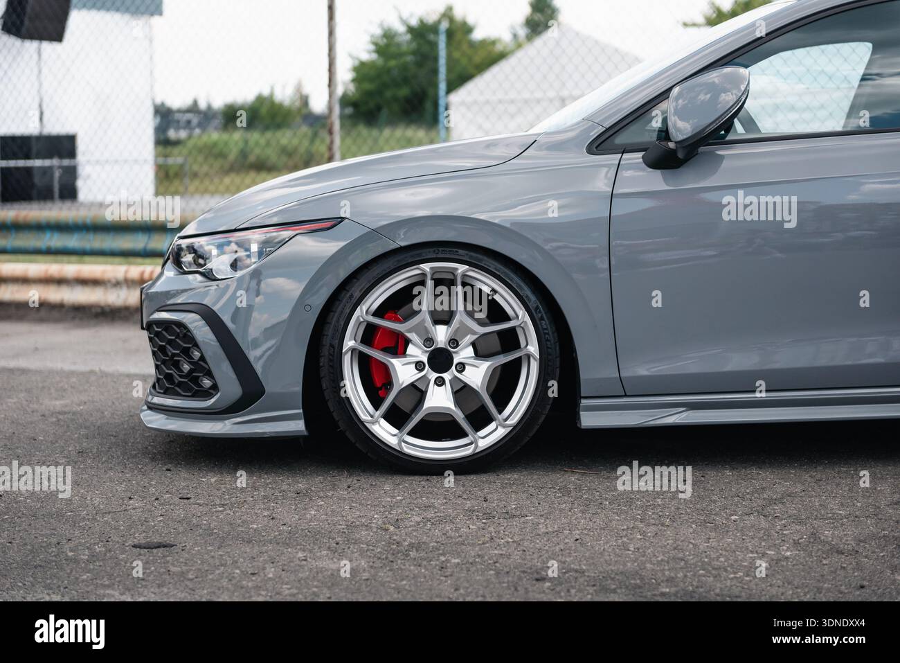Vista laterale ravvicinata della Volkswagen Golf grigio ardesia: Ruota anteriore, parafango, paraurti e faro della berlina sportiva parcheggiata su una strada. Foto Stock
