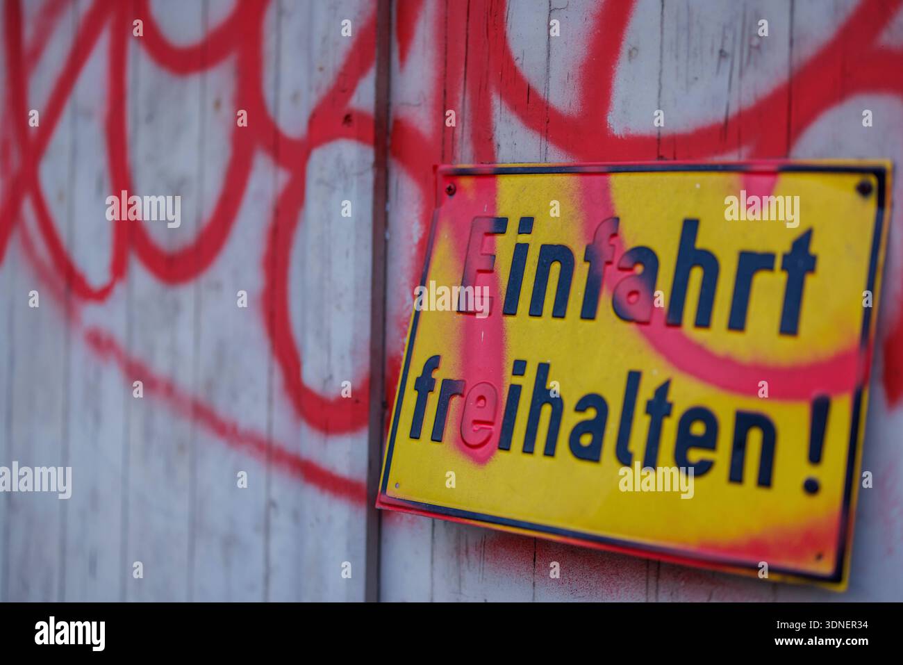 Einfahrt freihalten - Ein gelbes Hinweisschild mit der Aufschrift *Einfahrt freihalten*, das teilweise mit rotem Graffiti übersprüht wurde, hängt am 09.02.2026 an dem Holztor einer Garage in der Innenstadt von Osnabrück Niedersachsen, Deutschland. *** Einfahrt freihalten Un cartello giallo con l'iscrizione Einfahrt freihalten , parzialmente spruzzata con graffiti rossi, è appeso al cancello di legno di un garage nel centro della città di Osnabrück bassa Sassonia, Germania, il 09 02 2026 Foto Stock