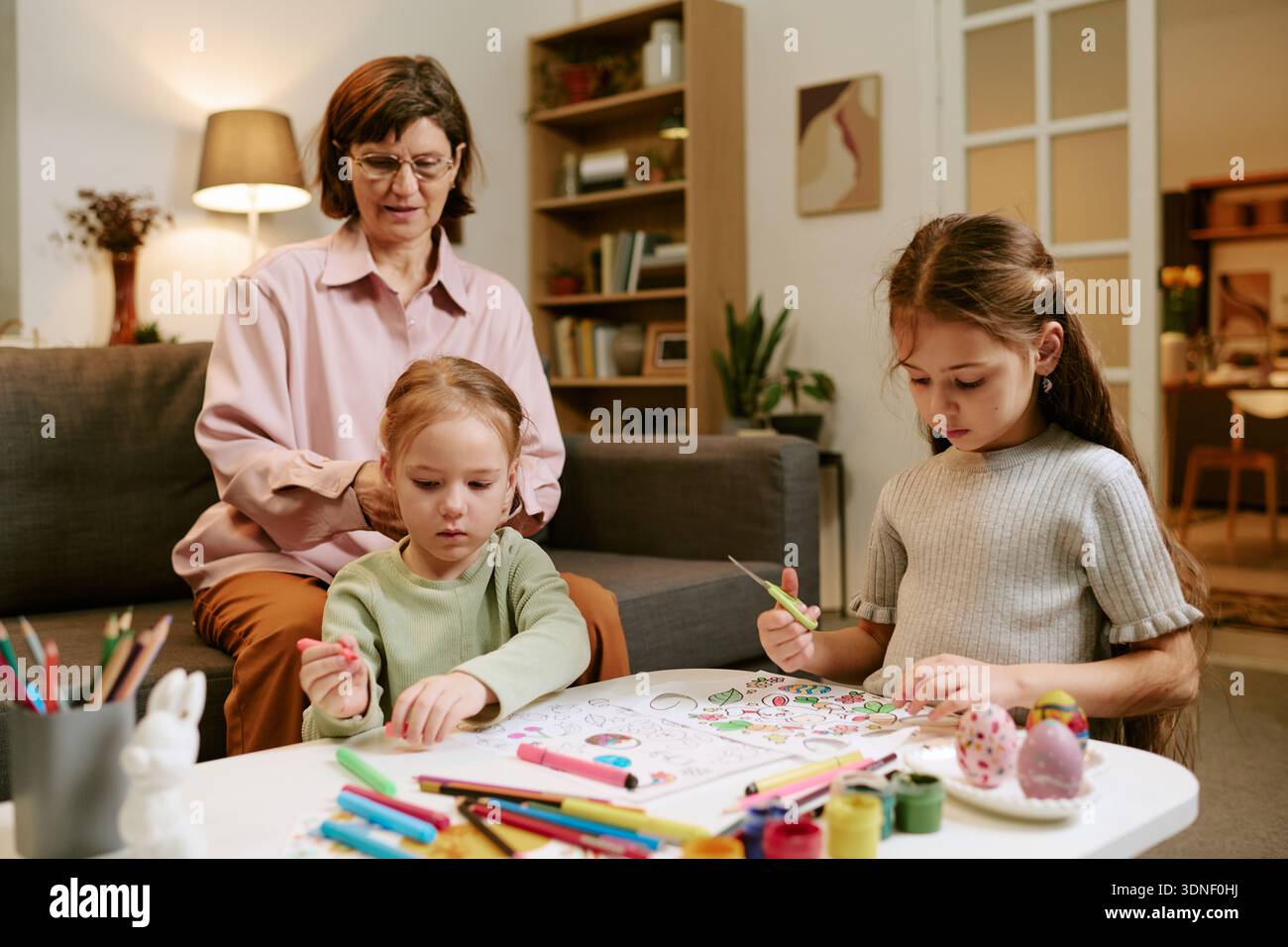 Nonna che supervisiona due ragazze che si uniscono Foto Stock