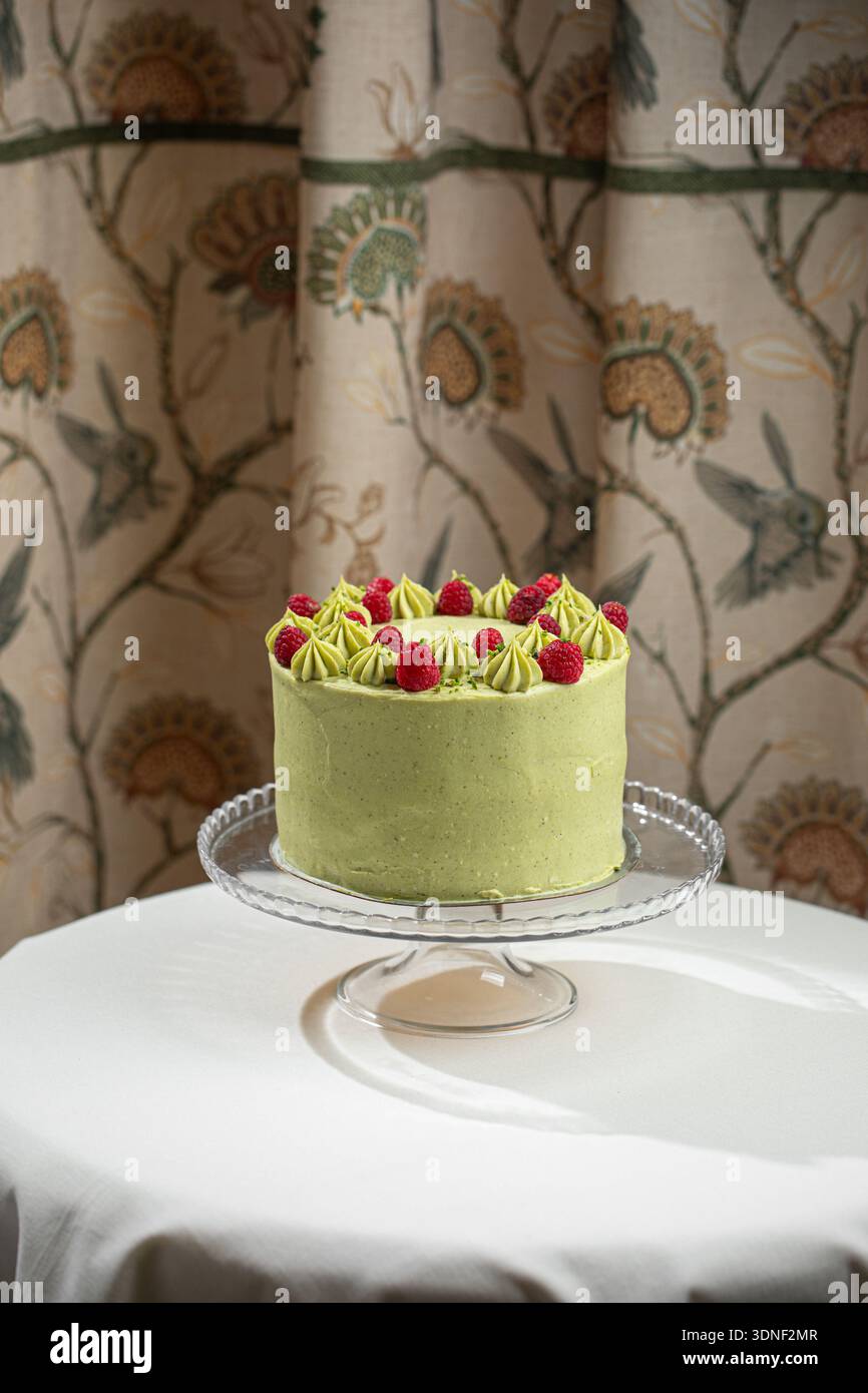 Torta di lamponi al pistacchio su supporto di vetro Foto Stock