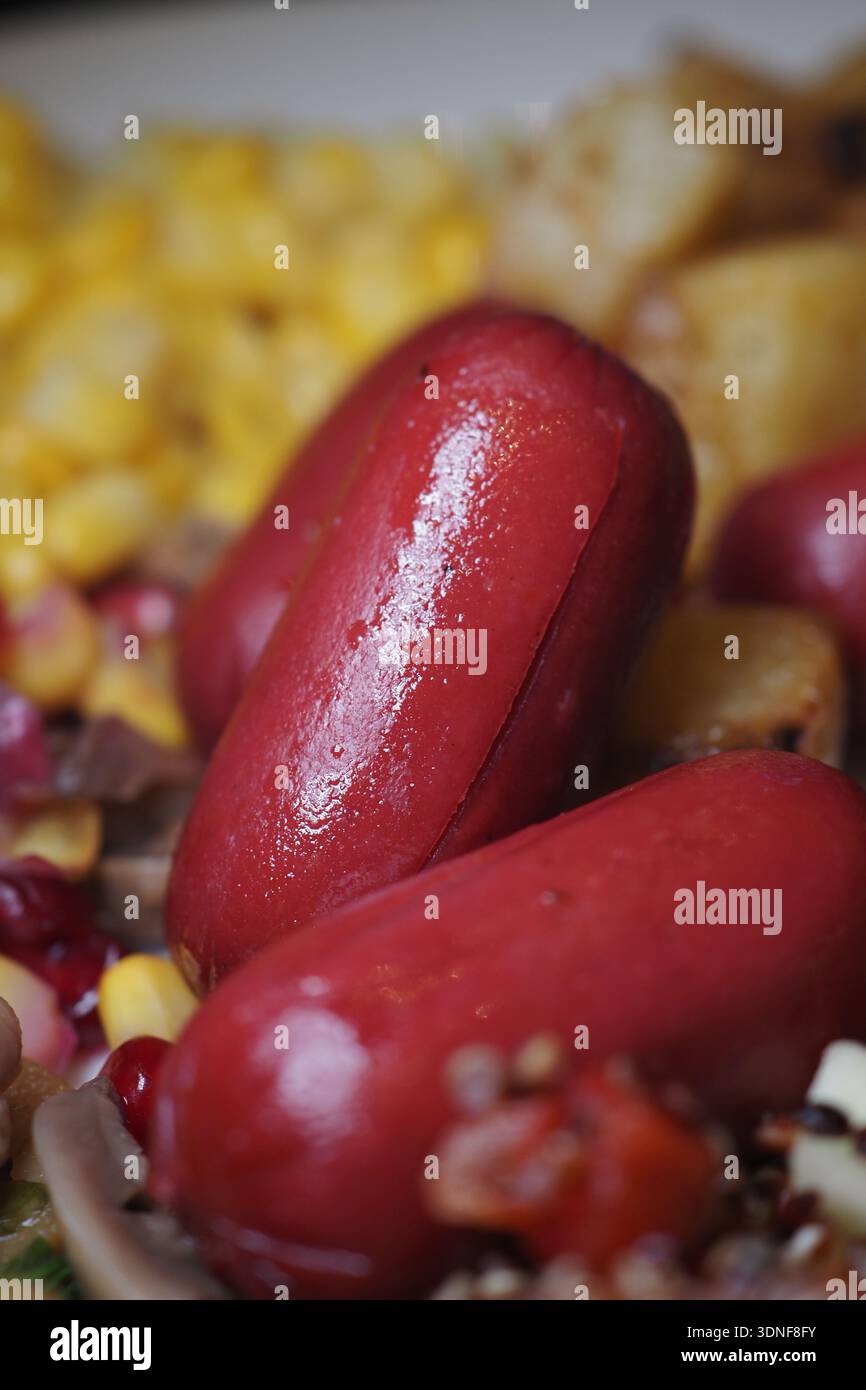 Hot dog colorati serviti con mais e patate su un piatto Foto Stock