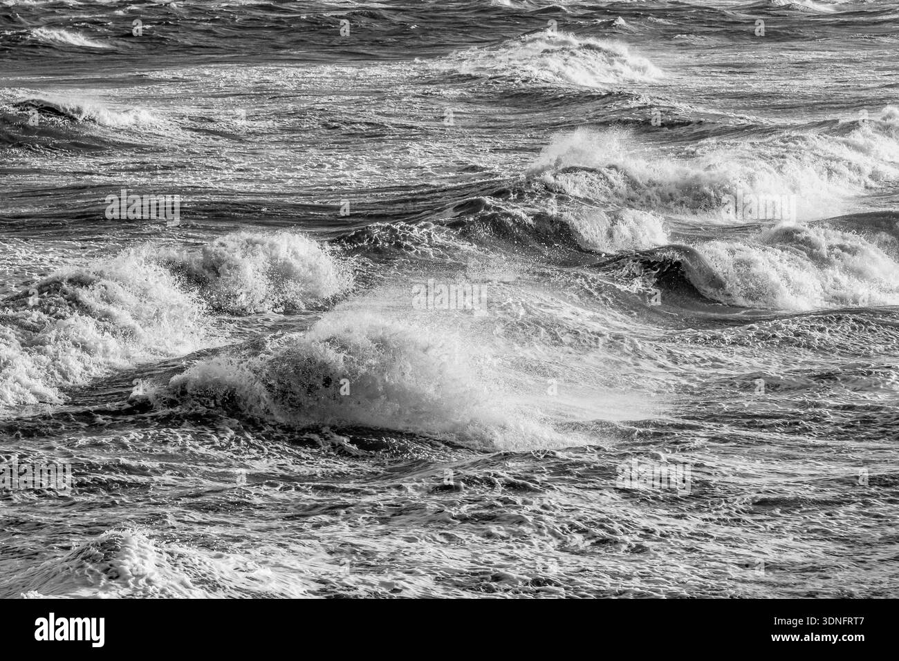 Vista in bianco e nero delle onde che si infrangono e degli spruzzi di mare nell'estuario di Mersey Foto Stock