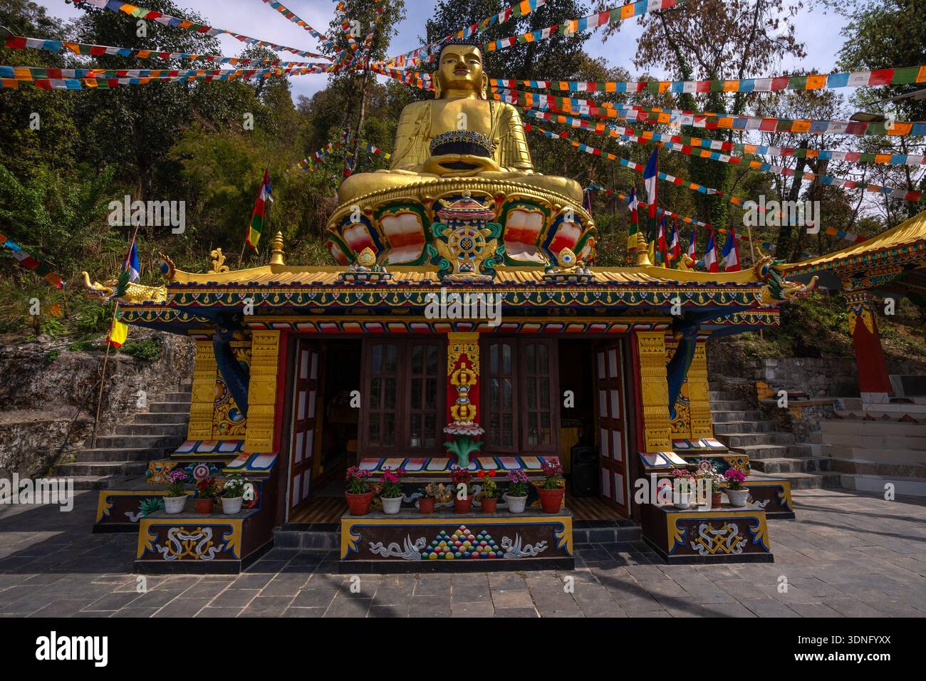 Santuario buddista con una statua dorata di un Buddha seduto e un paio di bandiere di preghiera intorno a Pokhara, Nepal. Foto Stock