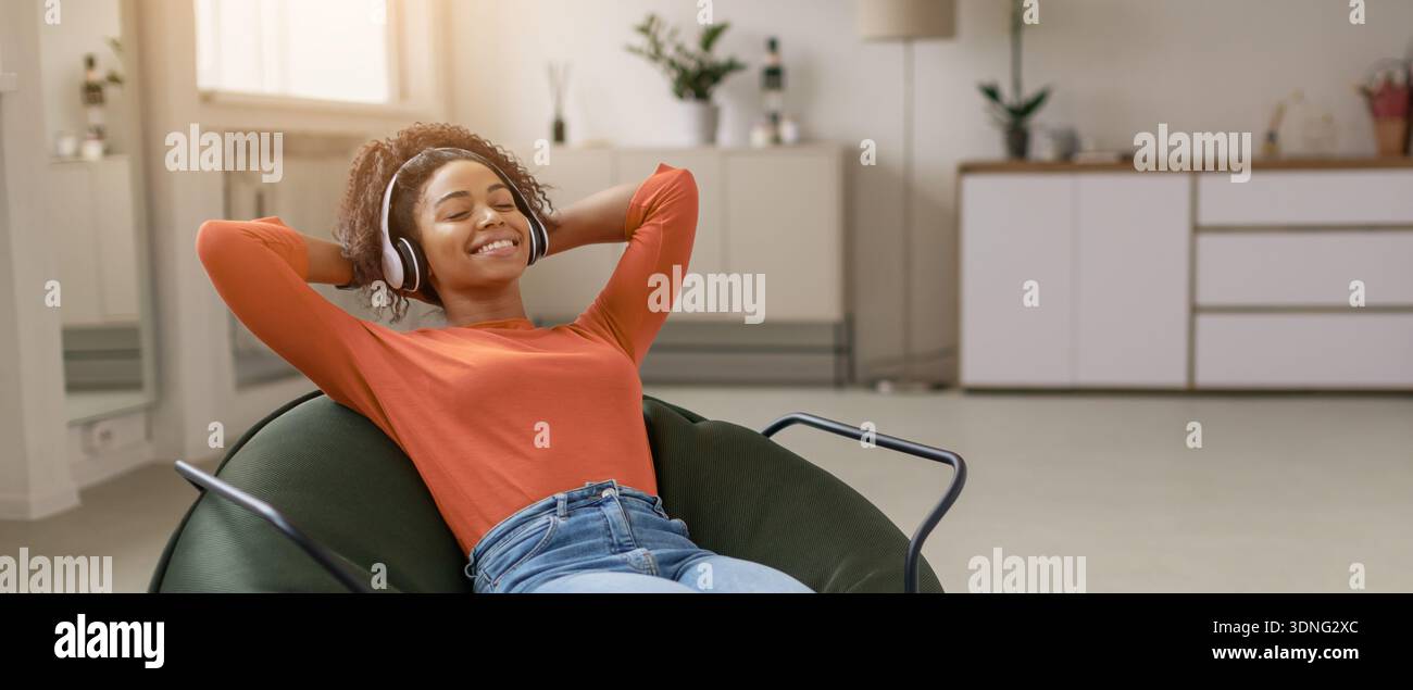 Una giovane donna ama ascoltare musica mentre si rilassa nella sua stanza durante il giorno Foto Stock