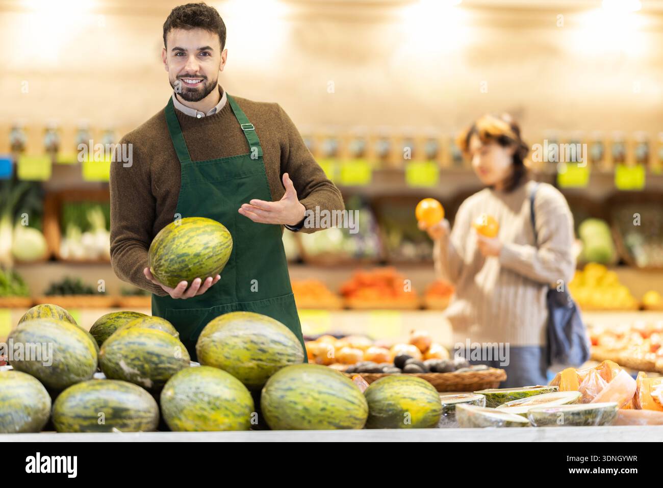 Uomini impiegati in uniforme che tengono il melone in un negozio di alimentari Foto Stock