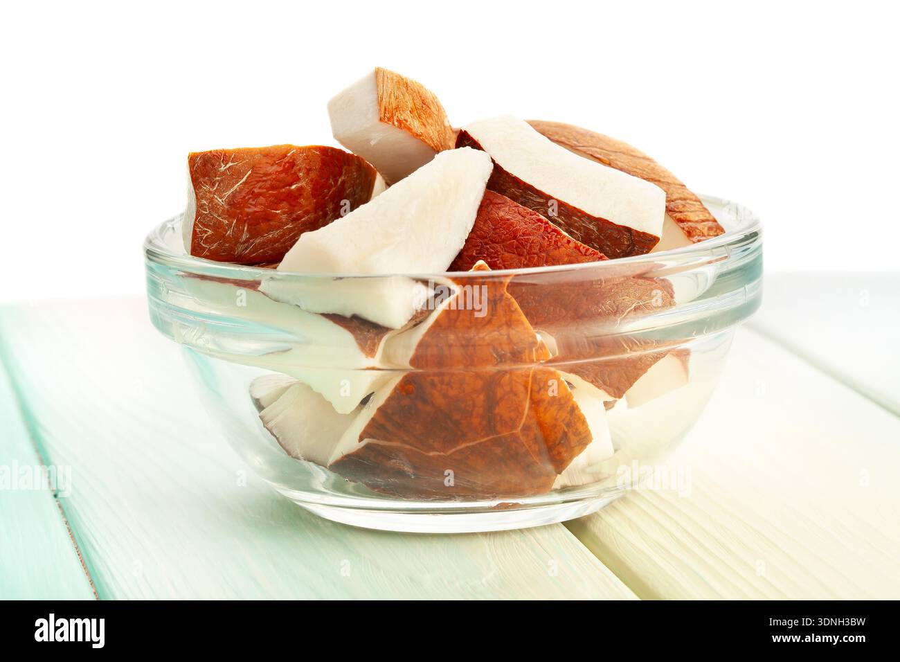 cocco tagliato a fette su sfondo di legno su sfondo bianco Foto Stock