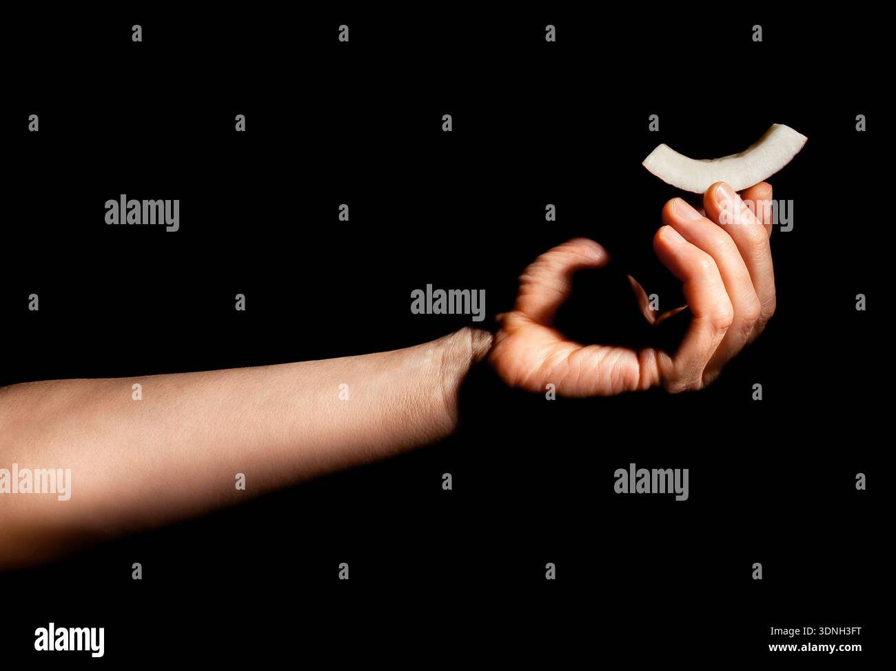 cocco a fette in mano su sfondo nero Foto Stock