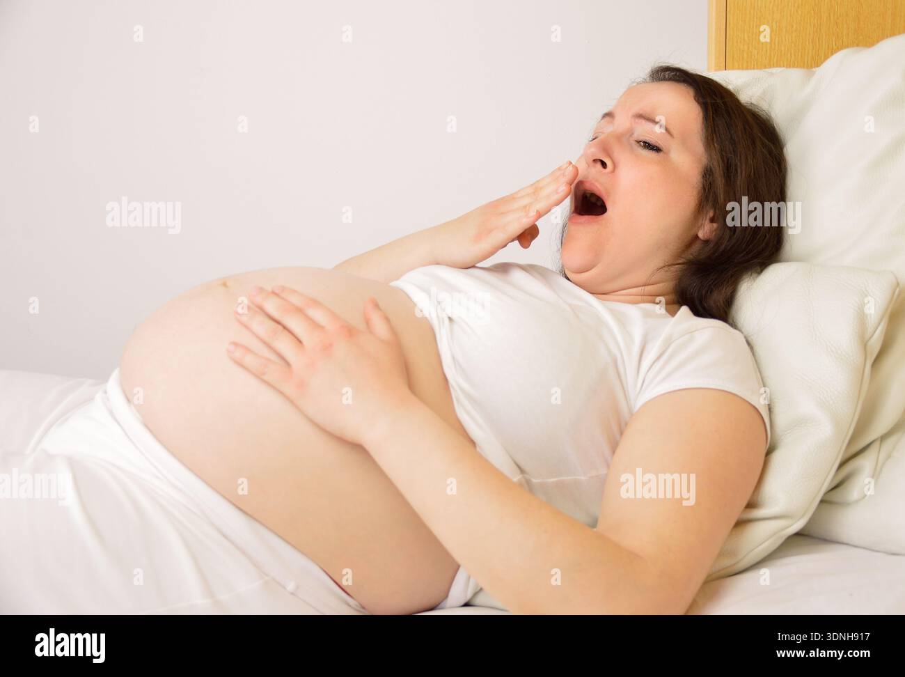 donna incinta che dorme sul suo letto a casa Foto Stock