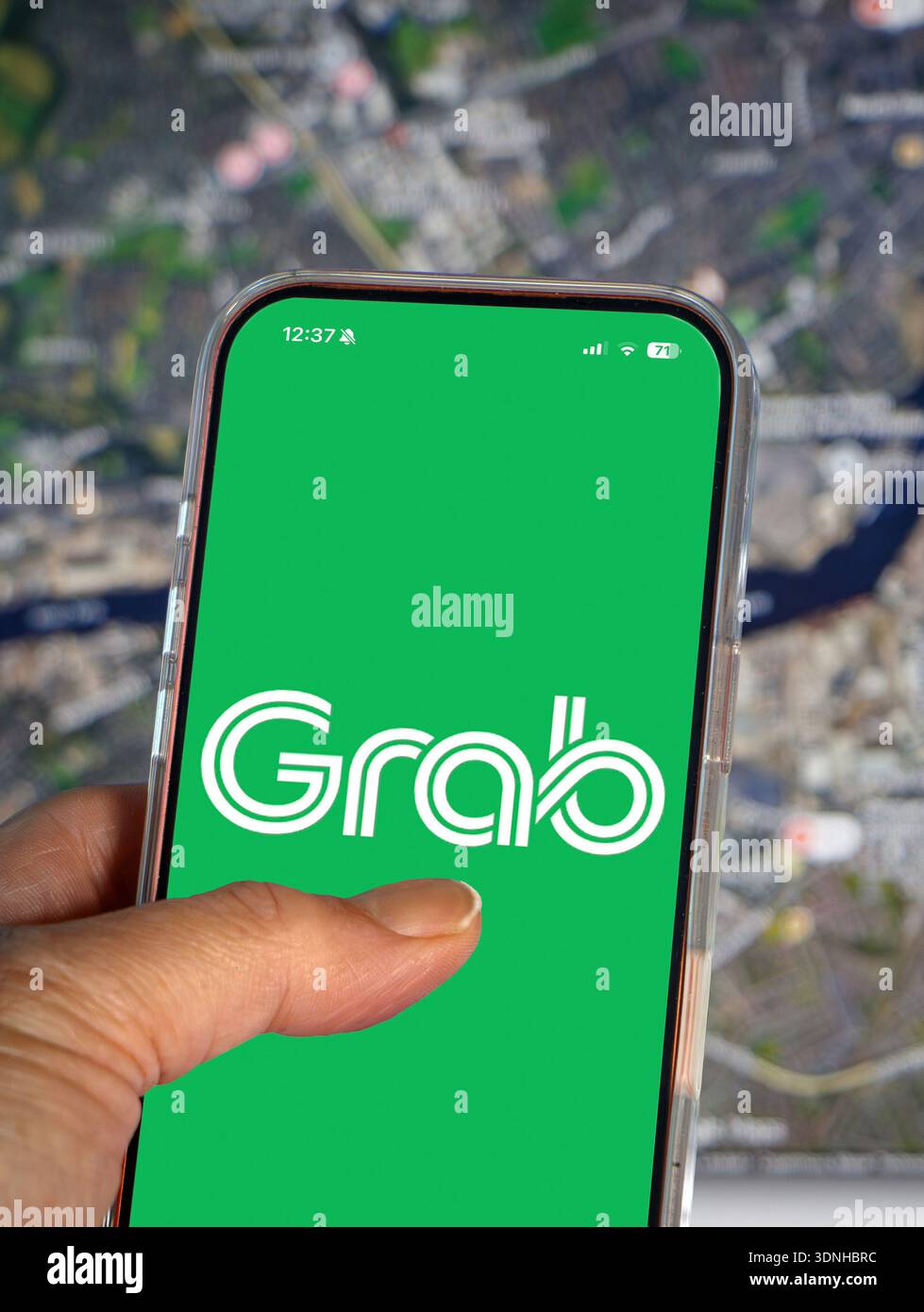 Persona che possiede uno smartphone che visualizza la schermata di avvio verde per l'applicazione di pagamento digitale e di chiamata "Grab ride-hailing", molto diffusa nel sud-est asiatico Foto Stock