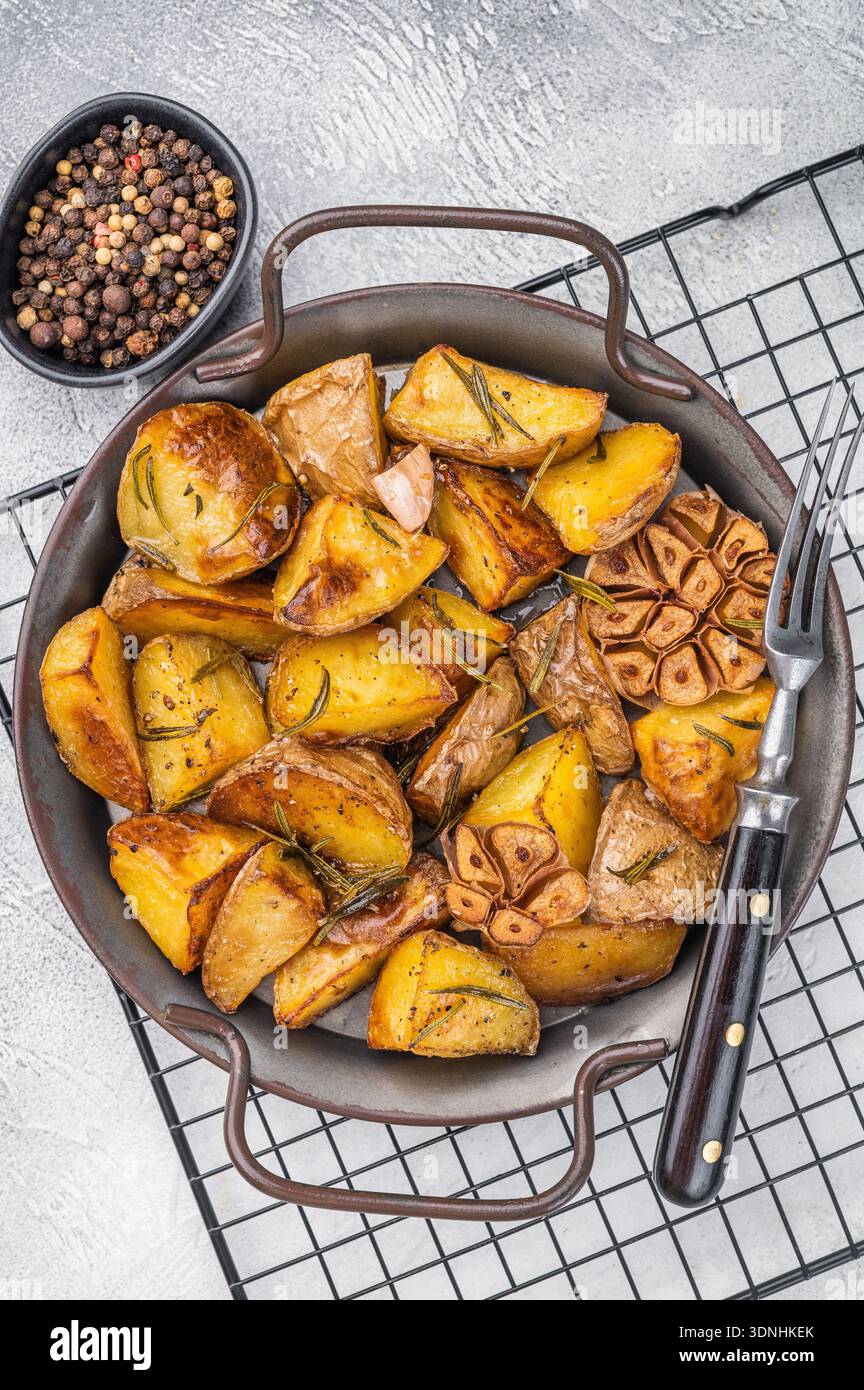 Patate al forno condite con rosmarino e aglio in una teglia di metallo. Vista dall'alto del tradizionale contorno vegetariano Foto Stock