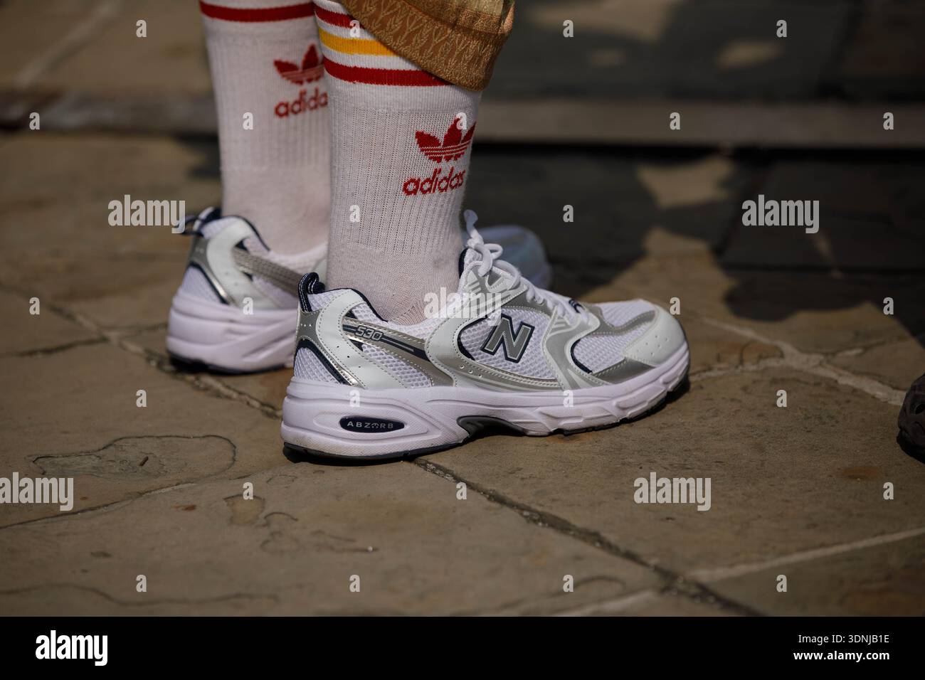 BANGKOK, THAILANDIA - 19 GENNAIO 2026: Turista maschile in costume tradizionale thailandese con scarpe da ginnastica in piedi su un pavimento in pietra, vista ad angolo alto Foto Stock