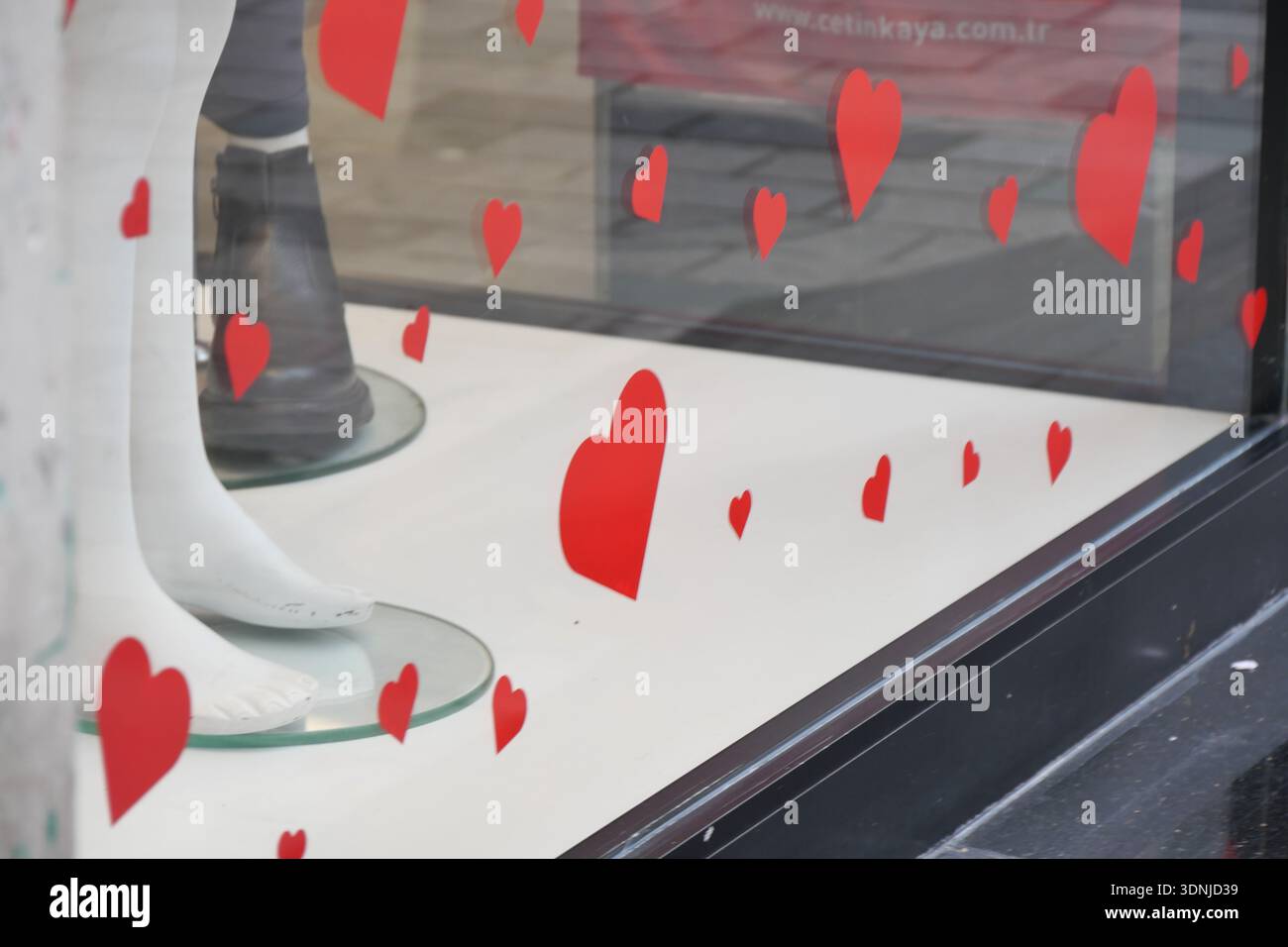 Le decorazioni a cuore rosso nella vetrina del negozio attraggono gli spettatori Foto Stock