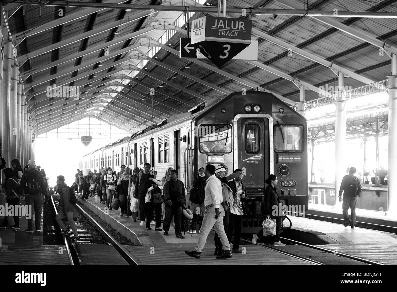 Una fotografia in bianco e nero che cattura una vivace piattaforma della stazione ferroviaria con i passeggeri che si preparano a salire a bordo di un treno d'epoca Foto Stock