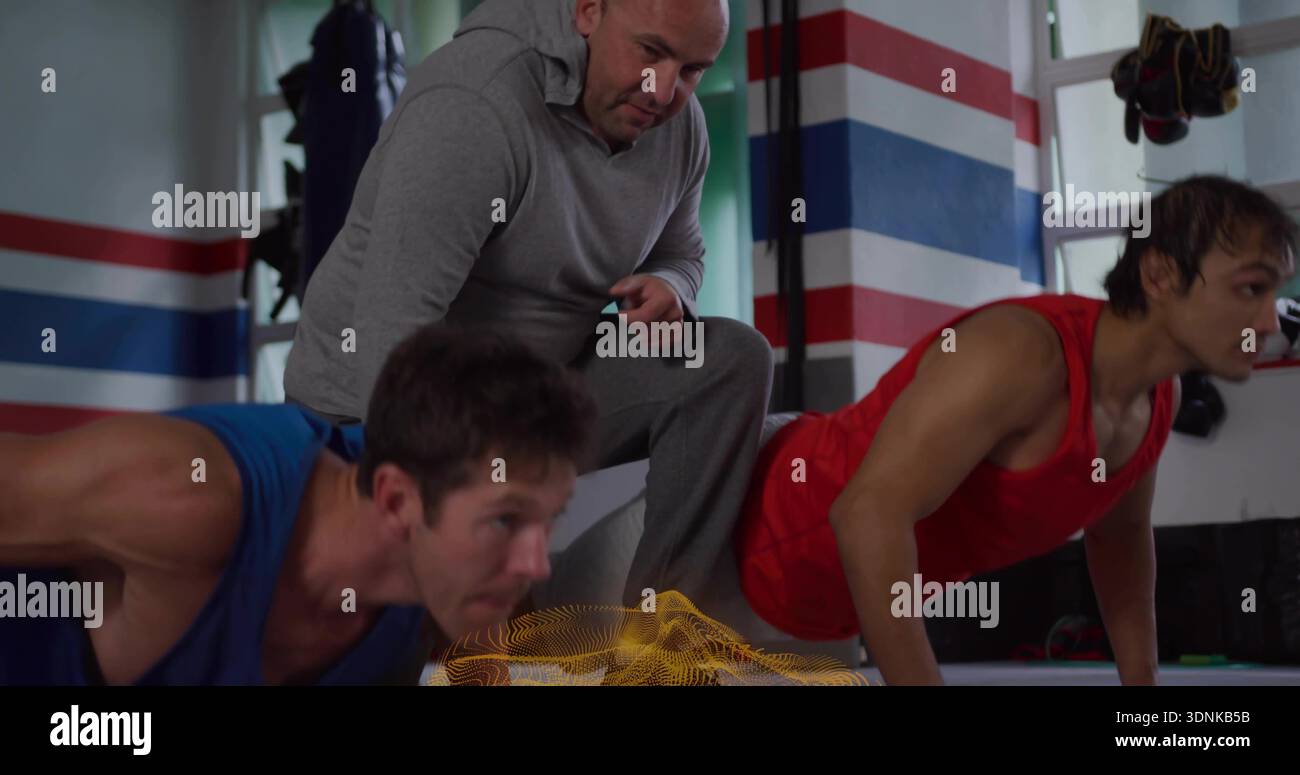Allenatore inginocchiato in tuta grigia che mette a segno gli atleti che fanno pushup con timer, blu o rosso senza maniche Foto Stock