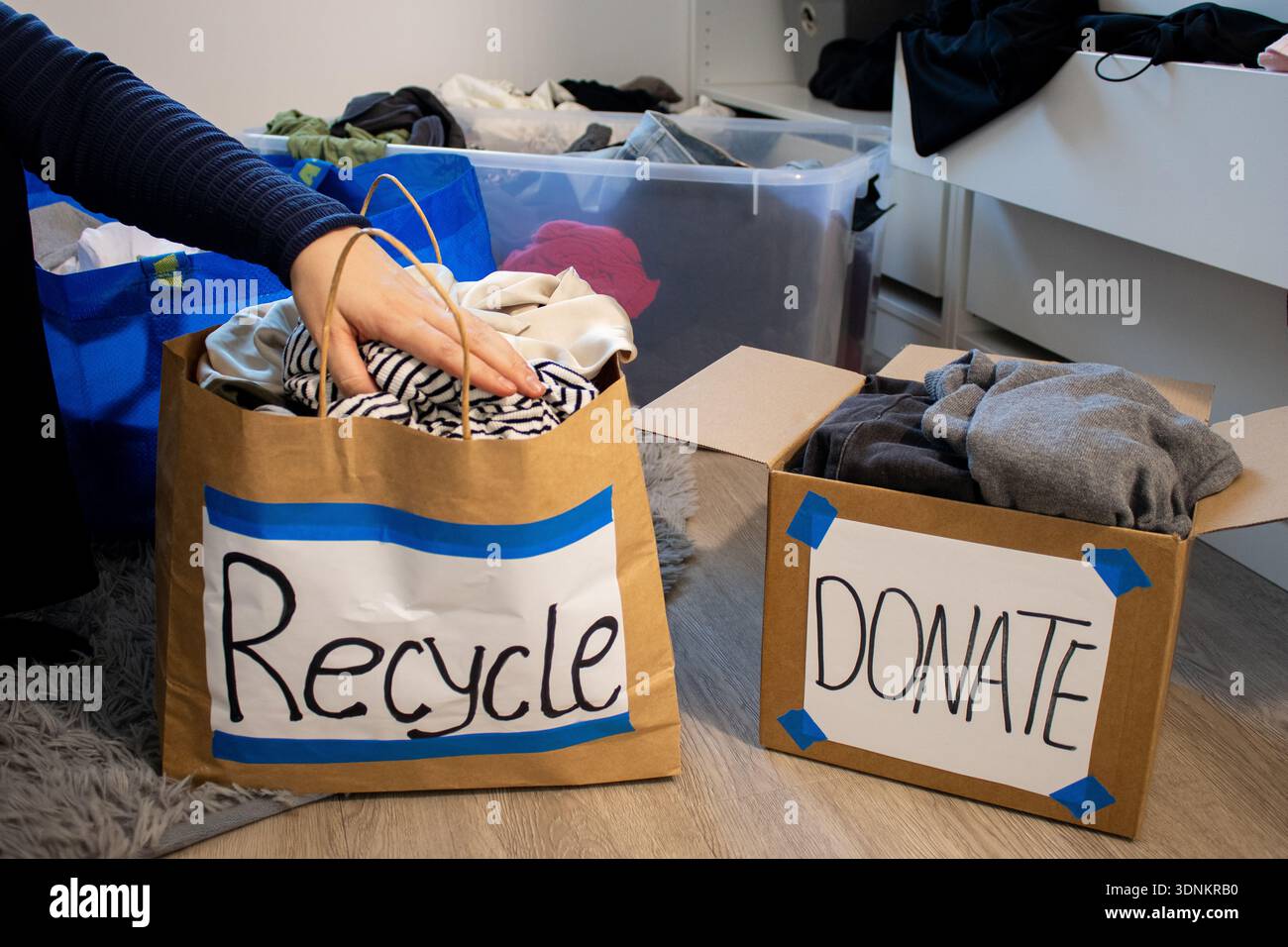 Donna che confeziona a mano abiti dal suo guardaroba per il riciclaggio e la donazione Foto Stock