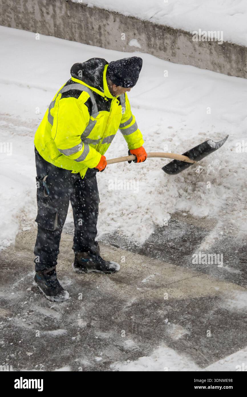 lavoratore che spalanca la neve sulla strada invernale Foto Stock