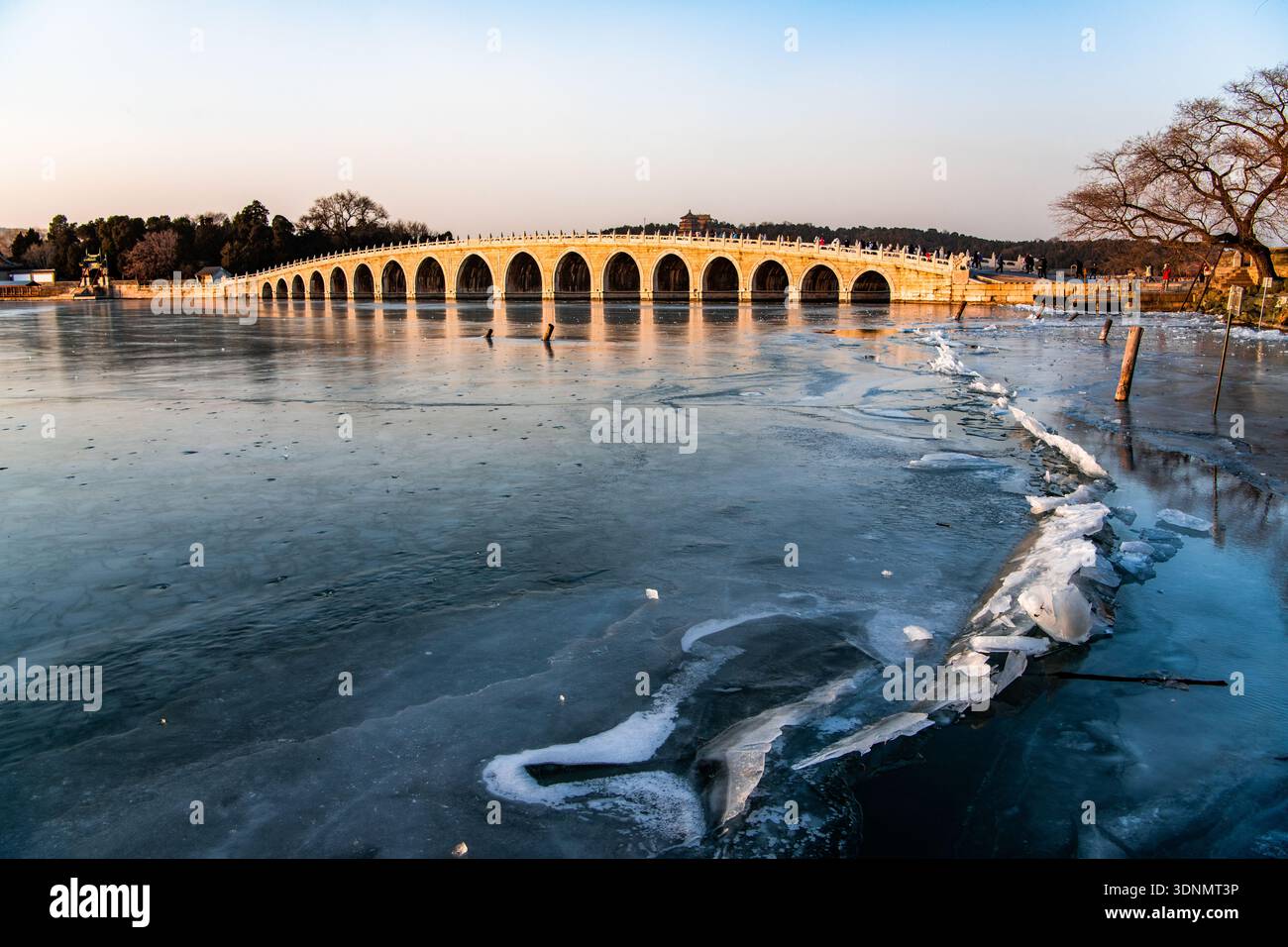 Il ponte del diciassettesimo arco al Palazzo d'Estate di Pechino illuminato dal famoso fenomeno della "luce dorata attraverso gli archi" al tramonto. Foto Stock