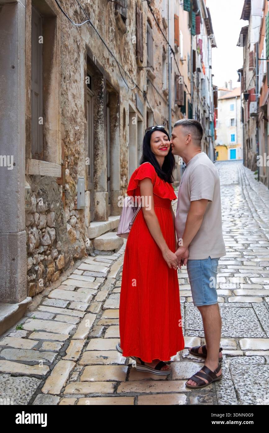 Una coppia romantica si baciava nella vecchia strada europea. Una giovane coppia che si tiene per mano e che condivide un bacio in una strada acciottolata in un'affascinante vecchia città europea Foto Stock