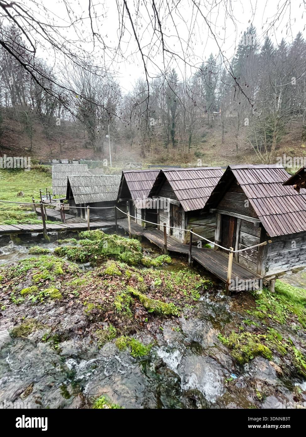 Tradizionali mulini ad acqua in legno a Jajce, Bosnia, circondati da corsi d'acqua e rocce muschiate, che creano un paesaggio rurale panoramico con patrimonio culturale e. Foto Stock