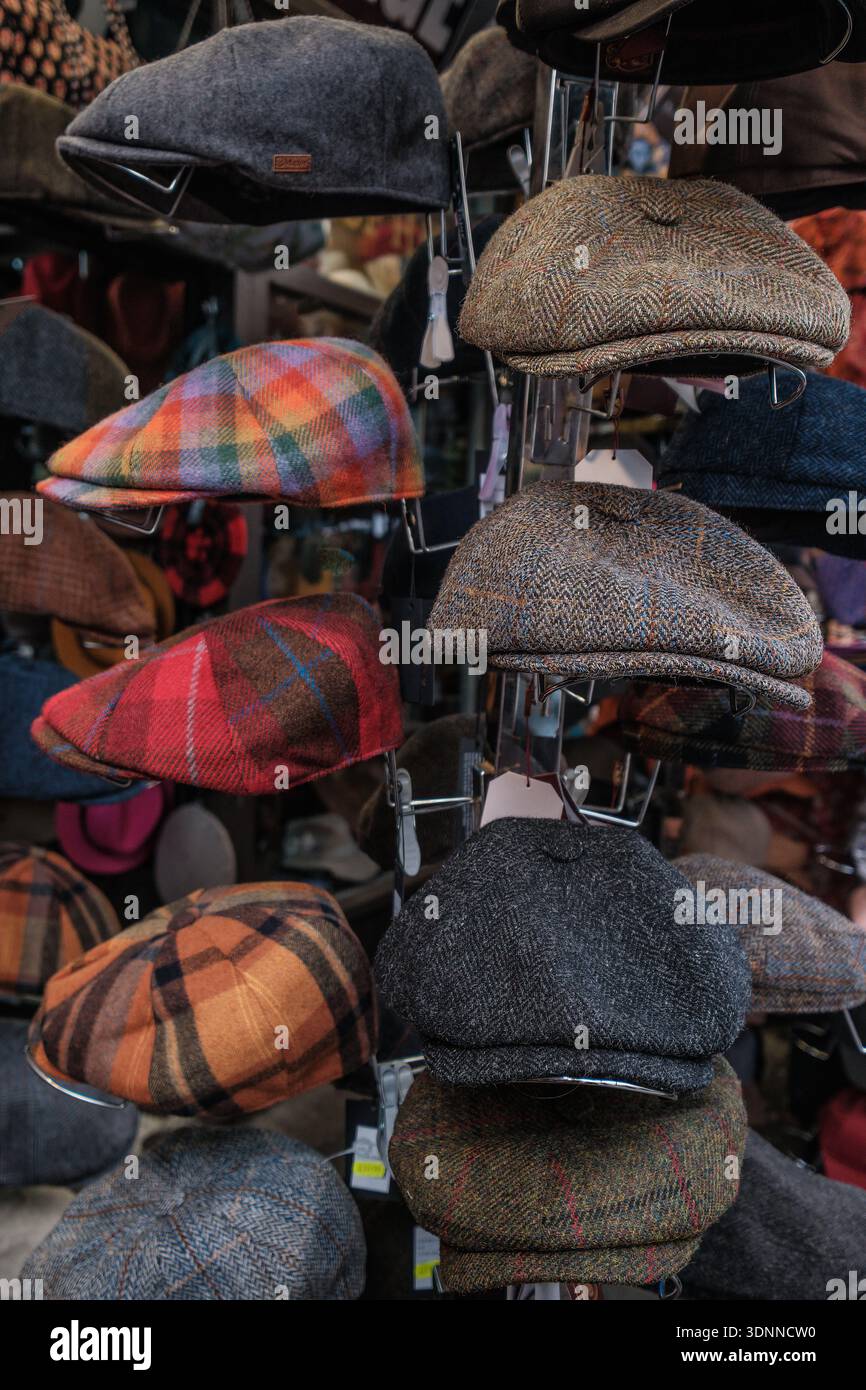 Berretti piatti tradizionali esposti in vendita in una bancarella del mercato di Londra, con una gamma di copricapi in tweed e motivi. Foto Stock