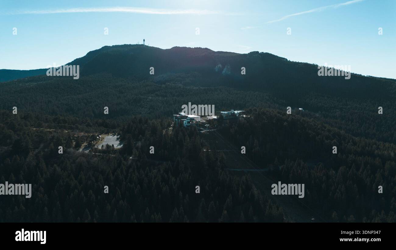Vista aerea della stazione della funivia di Sarajevo circondata da una fitta pineta e da creste di montagna. Le moderne infrastrutture si fondono con la natura, mostrando la città Foto Stock