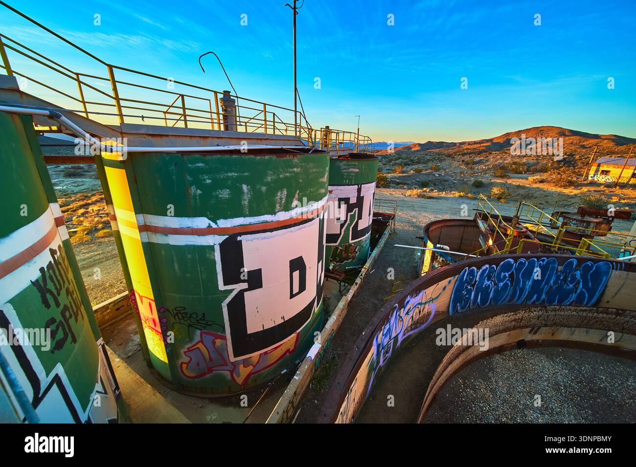 Serbatoi industriali abbandonati con Graffiti in Desert Landscape a Sunrise Foto Stock