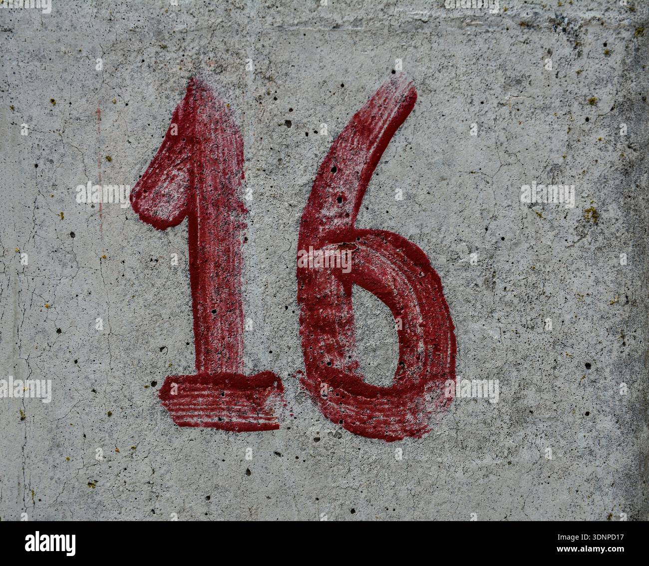 Rosso numero 16. Colore rosso metallizzato su sfondo in cemento. Foto Stock