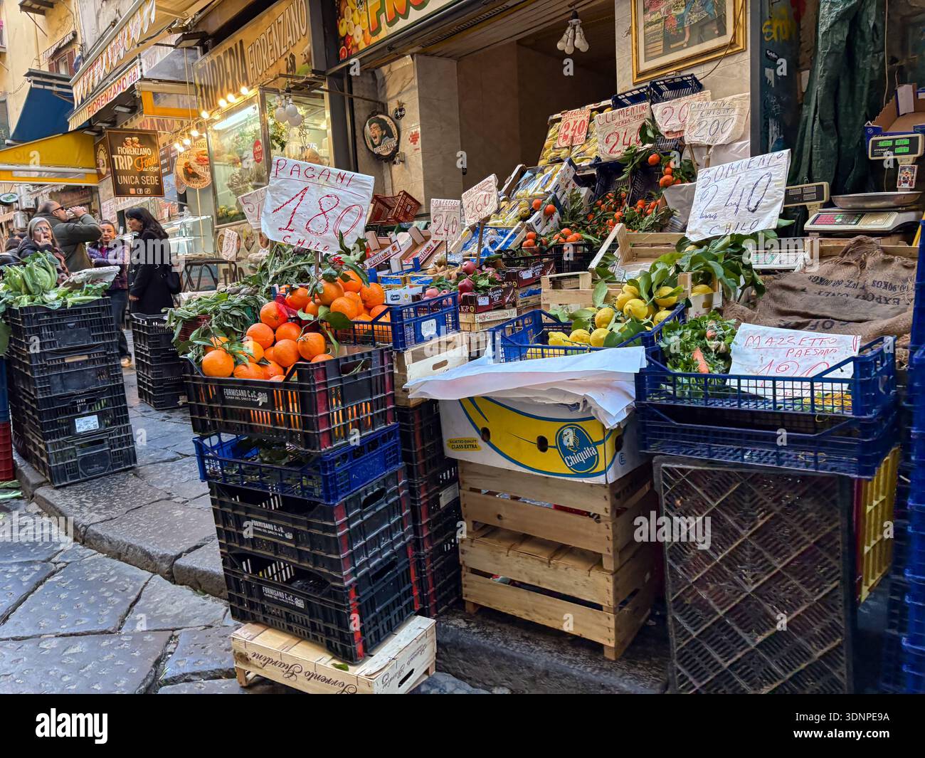 Mercato della Pignasecca, uno dei mercati di strada più antichi di Napoli, che espone arance, limoni e verdi in casse di plastica sull'antica strada in pietra. Foto Stock