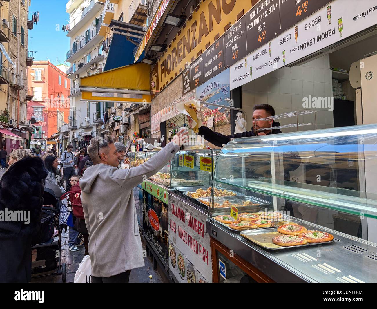Mercato della Pignasecca, uno dei più antichi mercati di strada di Napoli. Un venditore serve piccole pizze a un cliente nella strada stretta e vivace Foto Stock