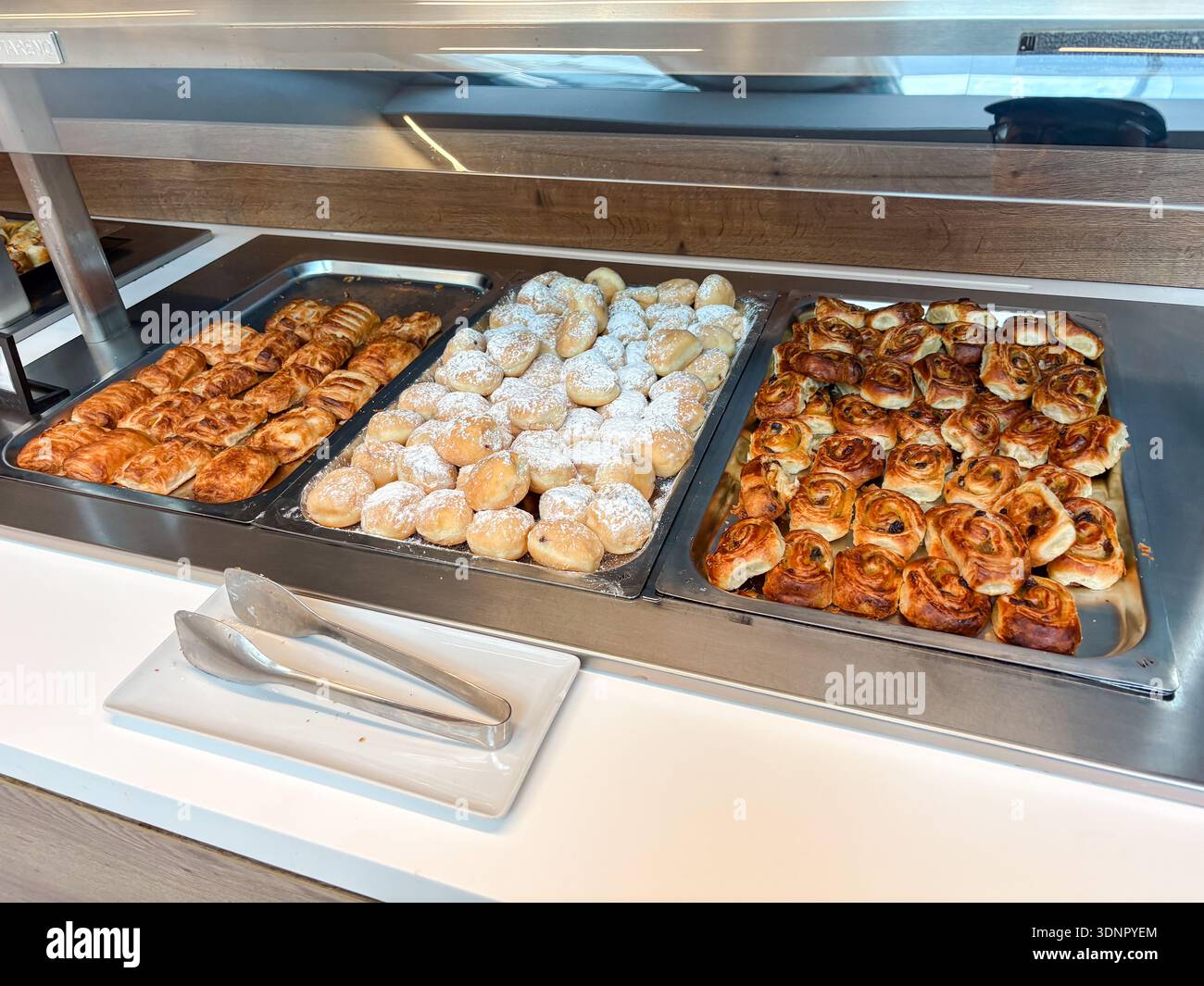 Colazione a buffet nella lounge dell'aeroporto con prodotti da forno: Ciambelle spolverate di zucchero, deviatoi e vortici di uva passa. Travel catering a Napoli, Italia. Foto Stock