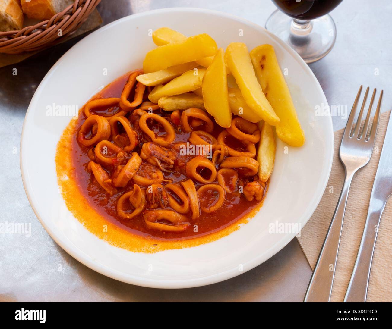 Anelli di calamari brasati in salsa americana con patatine fritte Foto Stock
