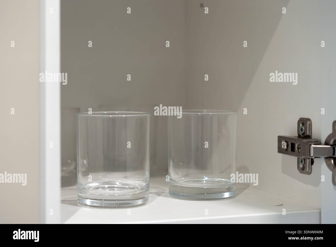 Vista ravvicinata di due bicchieri in vetro trasparente vuoti e puliti seduti su un ripiano bianco luminoso, che mostrano l'organizzazione della cucina e un moderno design per la casa semplice Foto Stock