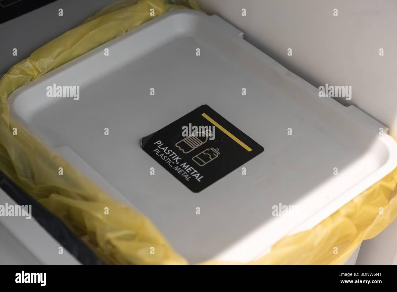 Contenitore di riciclaggio bianco vuoto con etichetta in plastica, metallo e rivestimento giallo, progettato per una corretta selezione dei rifiuti, che promuove abitudini ecocompatibili e sostenibili Foto Stock