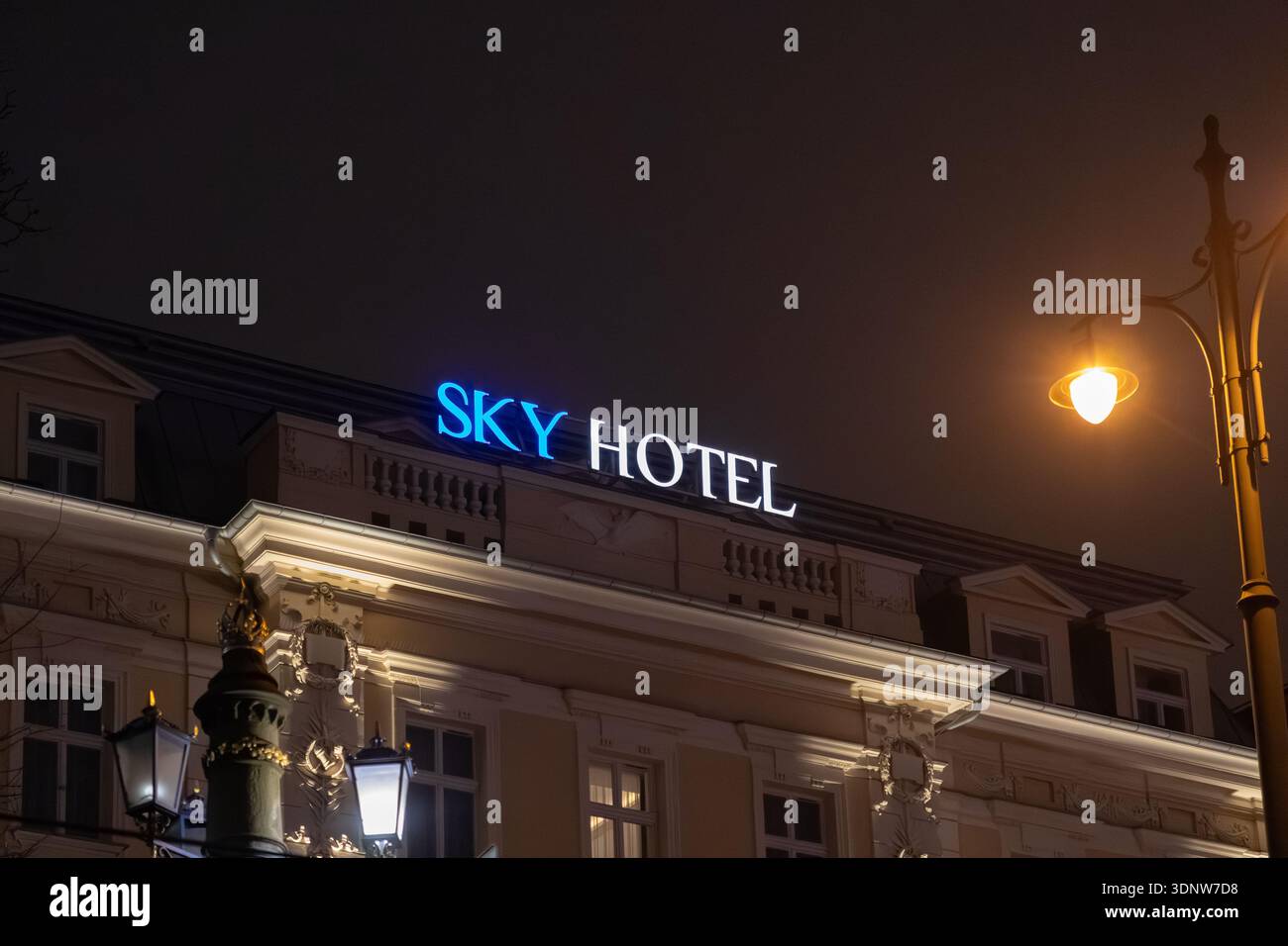 Cracovia, Polonia - 30 novembre 2025: Insegna DELL'HOTEL SKY, blu e bianco, si erge sull'edificio, faro per la sistemazione in città di notte Foto Stock