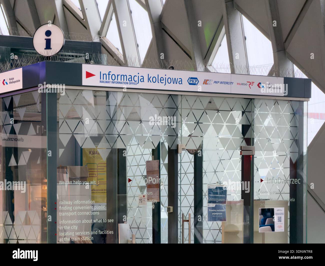 Poznan, Polonia - 30 novembre 2025: I passeggeri trovano informazioni essenziali sulla ferrovia presso il moderno ufficio di vetro, con PKP Intercity e Polregio log Foto Stock