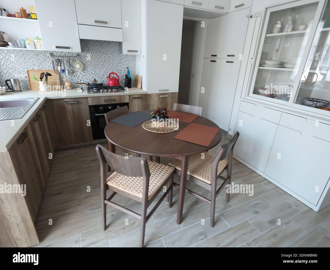 Design del soggiorno combinato con cucina, con credenza bianca. Set di mobili in legno con impiallacciatura in faggio, tavolo e sedie. Stile scandinavo Foto Stock