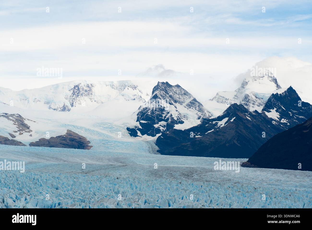 Vista del ghiaccio glaciale che si estende dalle cime innevate, contrastando nettamente con le scure montagne rocciose, il Los Glaciares National Park, Santa Foto Stock