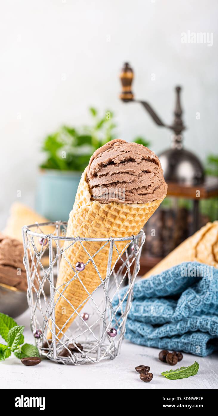 Cono gelato al cioccolato in un cestello decorativo con foglie di menta fresche e chicchi di caffè Foto Stock