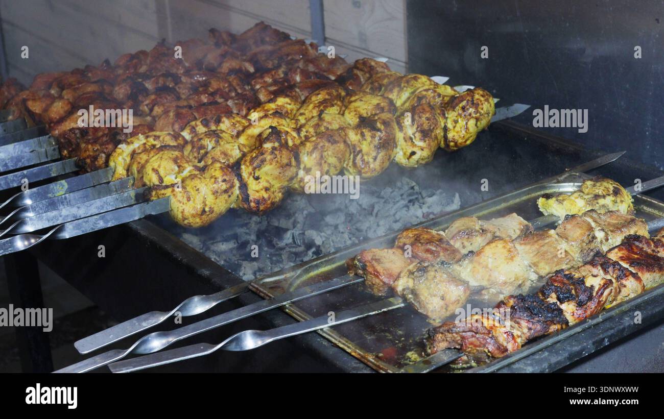 Un piatto di carne viene cucinato su una griglia. La carne viene cucinata in modi diversi, con alcuni pezzi grigliati e altri cotti in pa Foto Stock