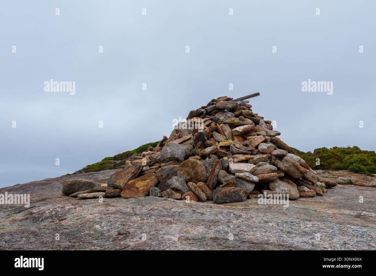 Un grande cairn fatto di rocce di granito impilate si trova sulla sommità di un affioramento di granito. Foto Stock