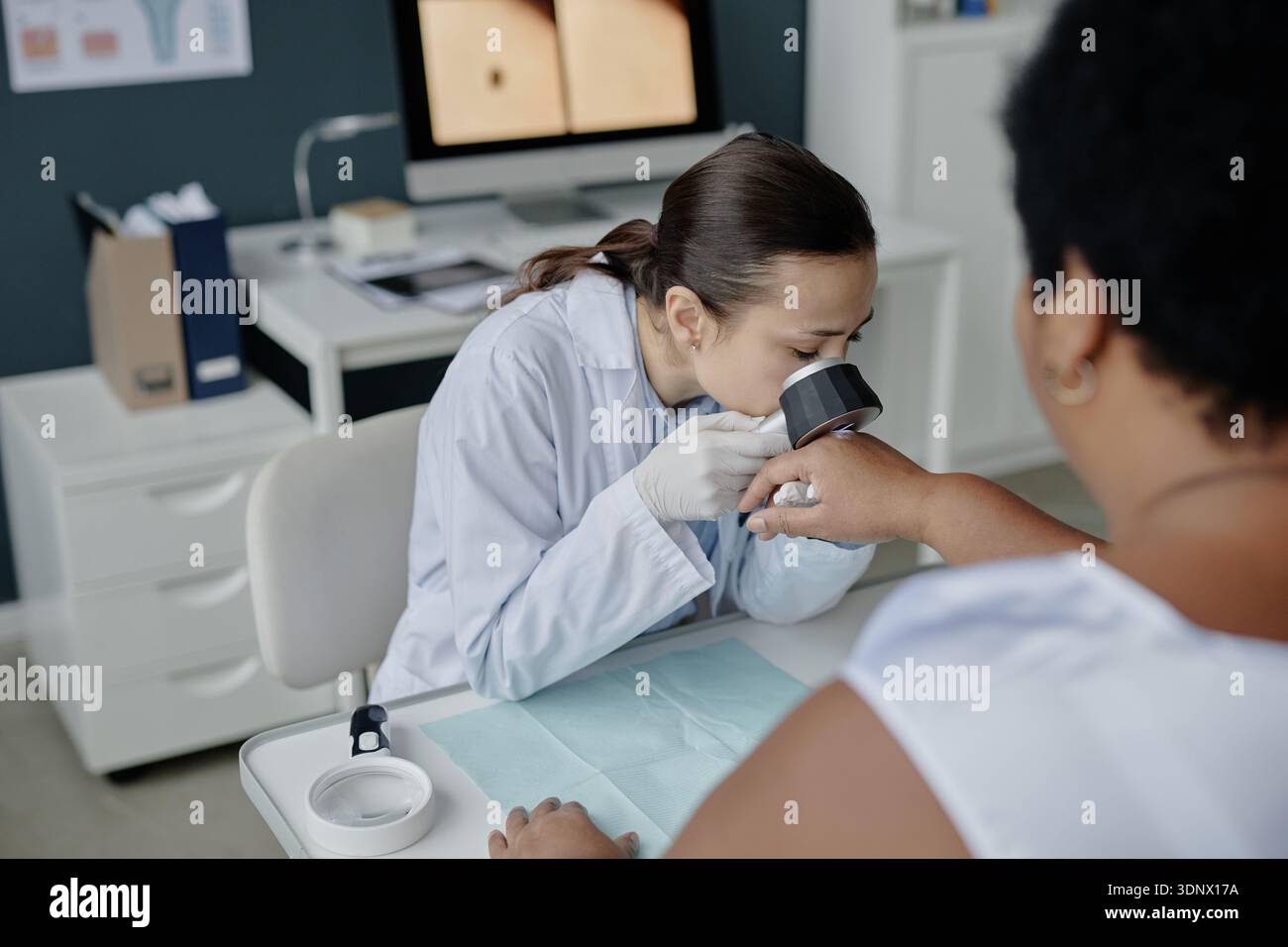 Giovane asiatica dermatologa femminile esaminando mano di mezza età donna nera Foto Stock