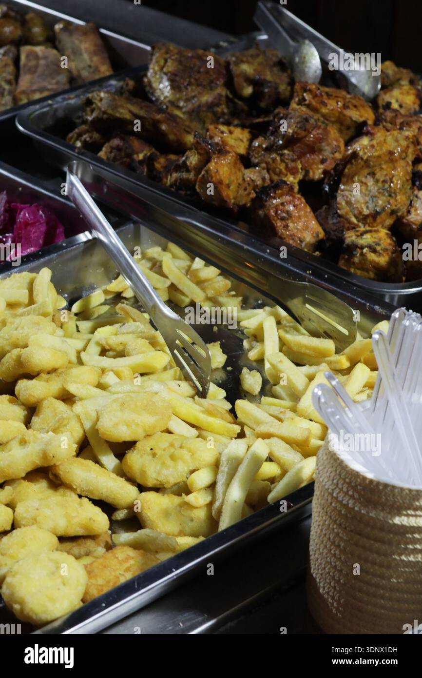 Un buffet con una varietà di piatti, tra cui patatine fritte e pollo Foto Stock