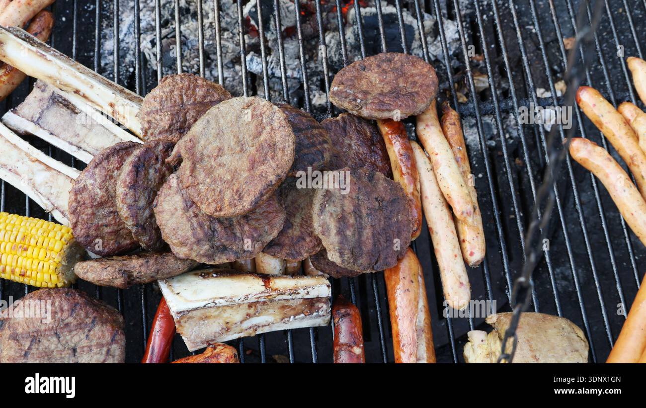 Una griglia con un pezzo di carne e un mucchio di hot dog Foto Stock