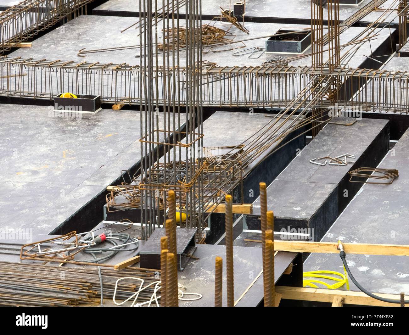 Vista di un cantiere con un sistema dettagliato di fondamenta e casseforme. Numerosi rinforzi in acciaio e lastre di cemento mettono in risalto il motore Foto Stock