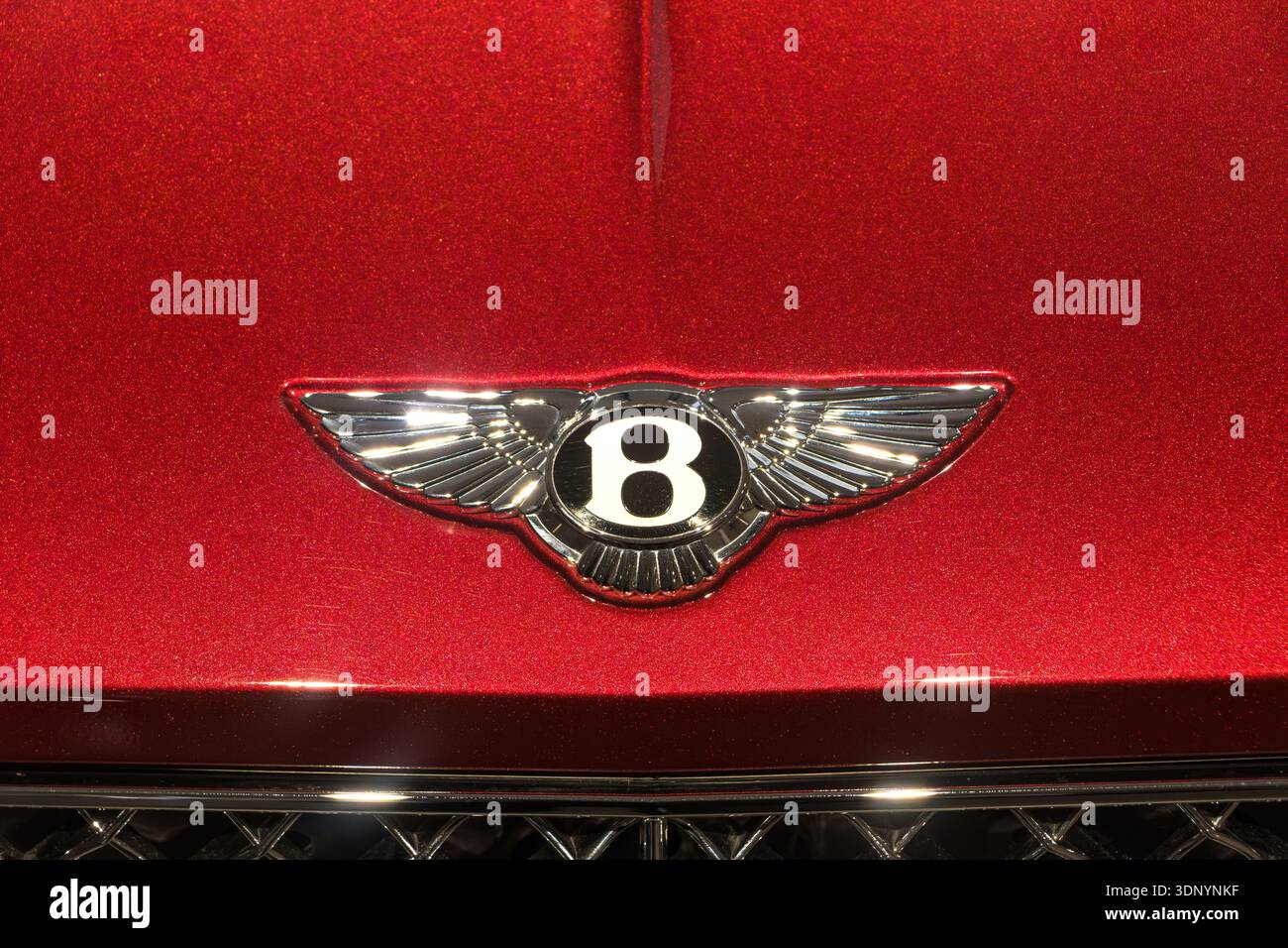 Primo piano sull'iconico emblema cromato alato con la lettera B sul cofano di una lussuosa e vivace auto Bentley rossa Foto Stock