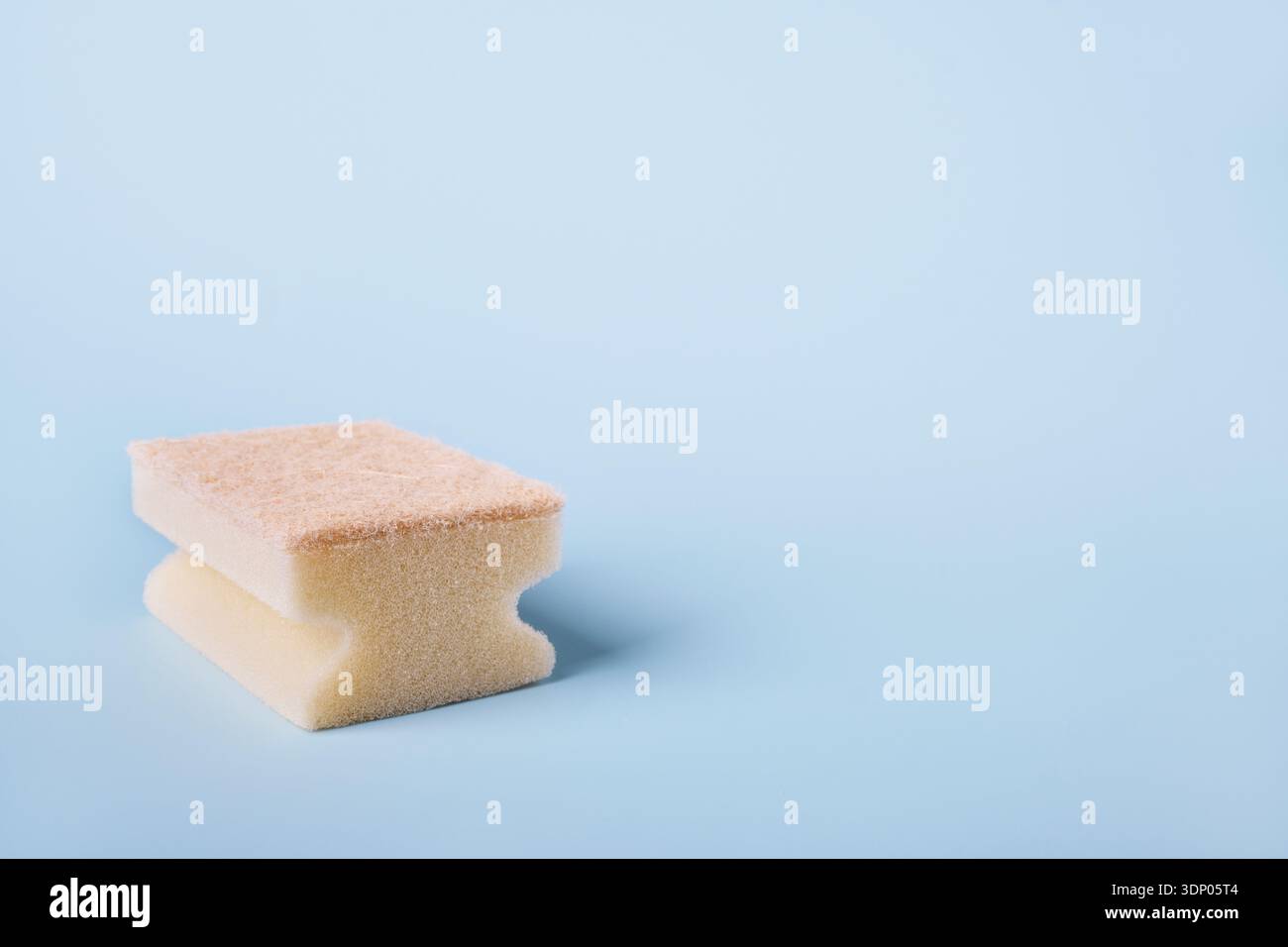 Spugna da cucina con superficie abrasiva su sfondo blu, che rappresenta l'igiene Foto Stock