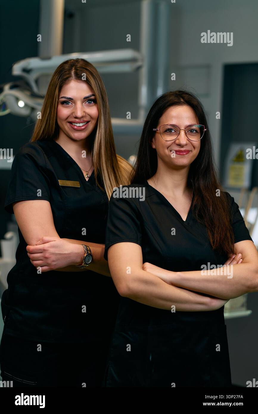 Due professionisti medici fiduciosi in Scrubs stanno insieme in un ambiente ospedaliero moderno in posa per foto Foto Stock