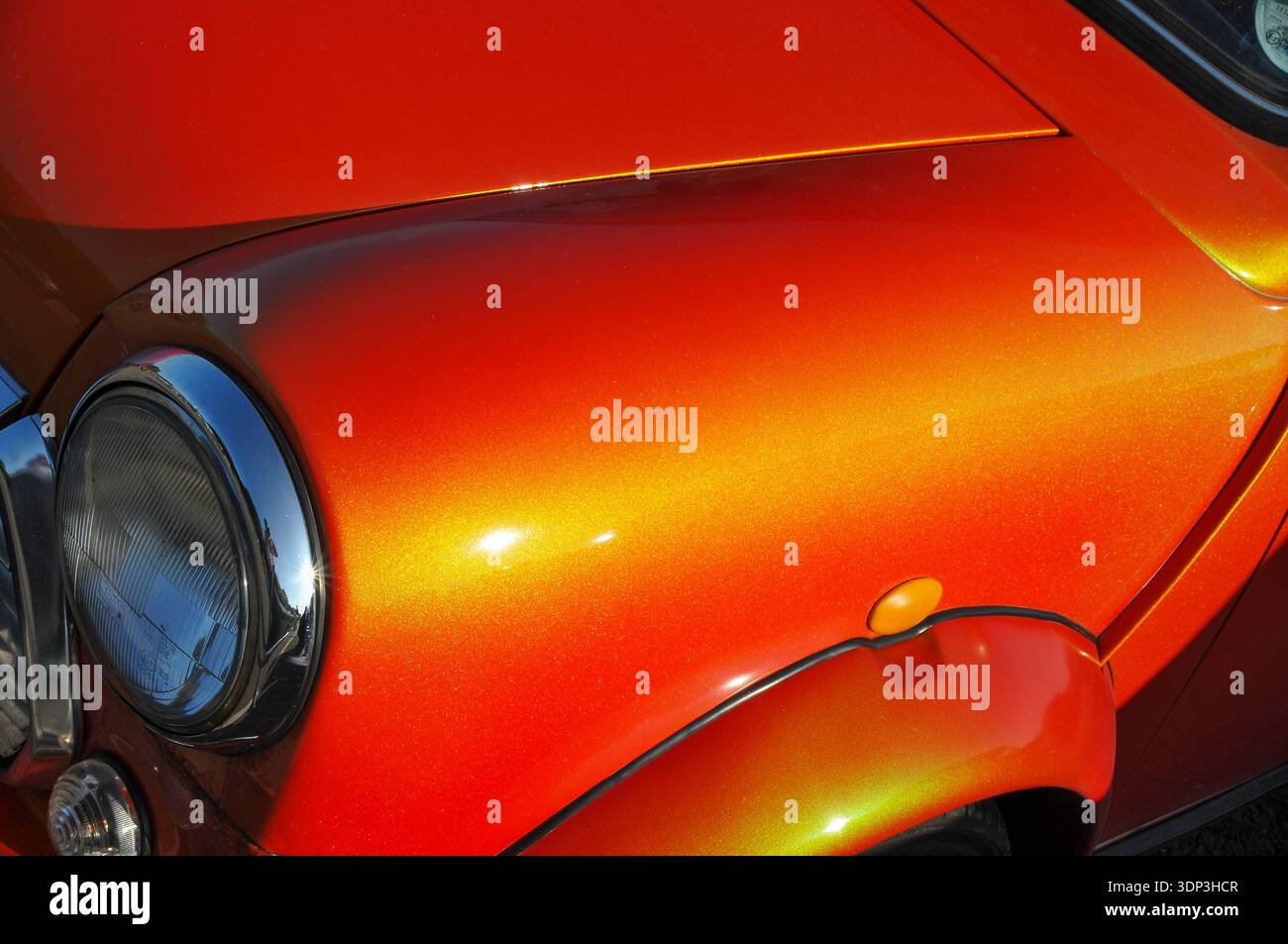 Dettaglio ravvicinato di un complessivo faro e ala Mini Cooper metallizzata arancione vivace Foto Stock