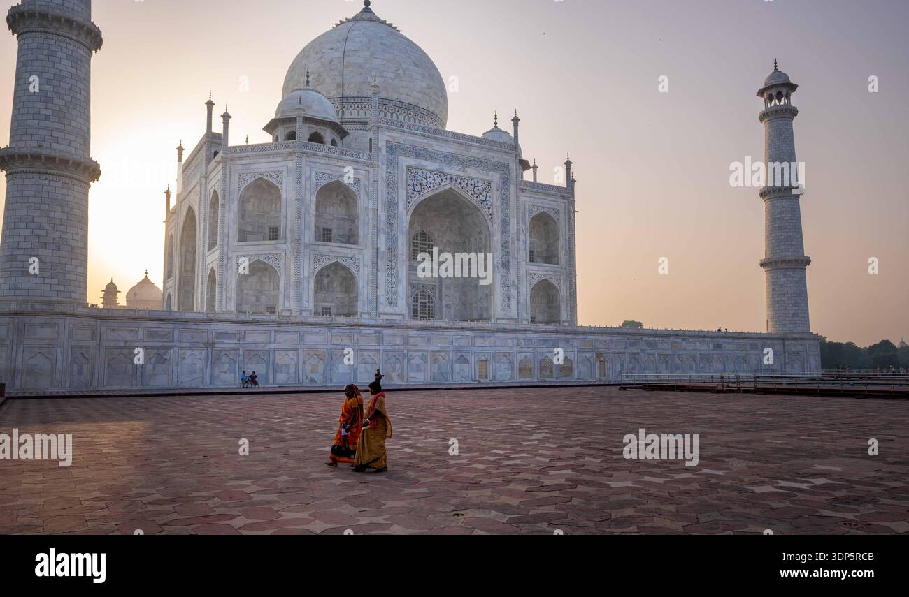 Taj Mahal alla luce del mattino con due figure che camminano attraverso l'area vuota del cortile. Foto Stock